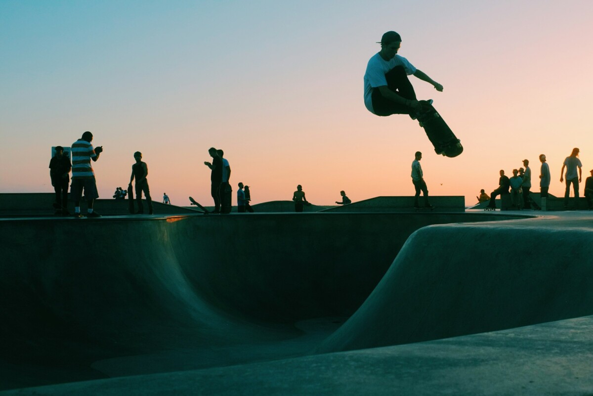 people skating in a skate park over a sunset